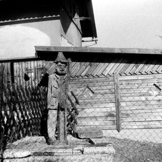 Statue of man in winter attire near fence.