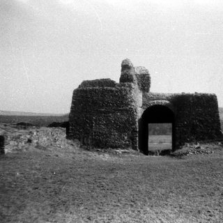 Ruined stone watchtower or gatehouse in rural landscape.
