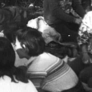 Campfire gathering of people in forested area.