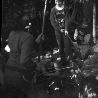 Campfire gathering of people in forested area.