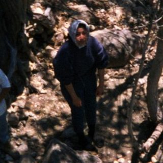 People hiking near a shallow stream.