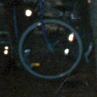 Woman sitting alone outdoors at night, holding drink.