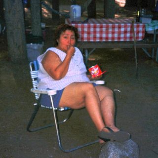 Woman sitting alone outdoors at night, holding drink.
