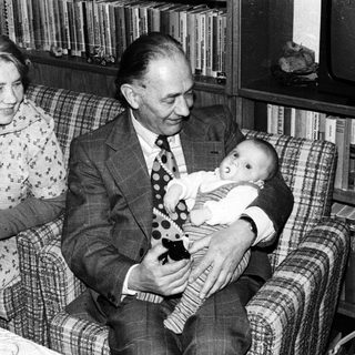 Older couple holding and smiling with baby indoors.