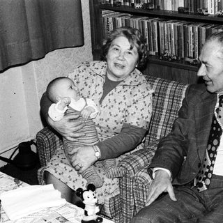 Family portrait with elderly couple and baby indoors.