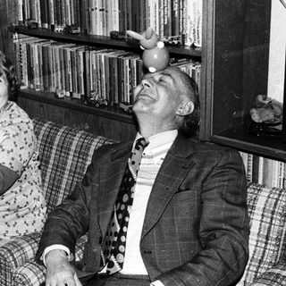 Two elderly people laughing while holding a cat.