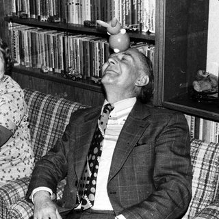 Two elderly people laughing while holding a cat.