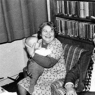 Two elderly people laughing while holding a cat.