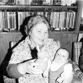 Woman holding baby in arm indoors.