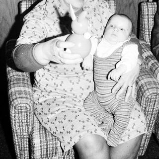 Woman holding baby in arm indoors.
