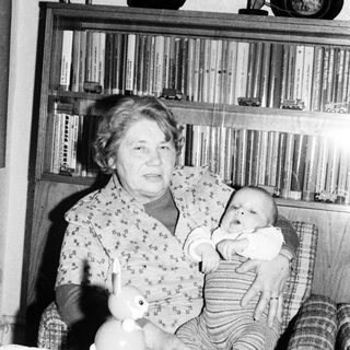 Woman holding baby in vintage indoor setting.