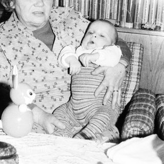 Woman holding baby in vintage indoor setting.