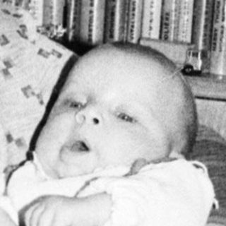 Woman holding baby in vintage indoor setting.