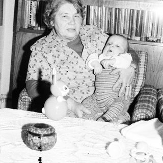 Woman holding baby in vintage indoor setting.
