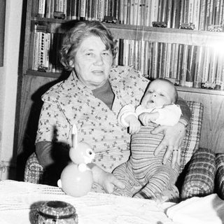 Woman holding baby in vintage indoor setting.