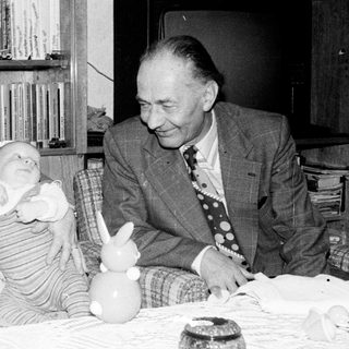Older couple holding and smiling with baby indoors.