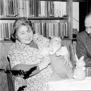 Older couple holding and smiling with baby indoors.