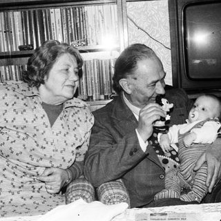 Family moment with elderly couple and baby indoors.