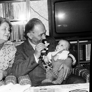 Family moment with elderly couple and baby indoors.
