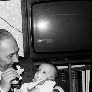 Family moment with elderly couple and baby indoors.