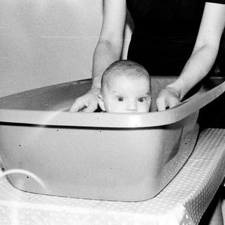Baby sitting in a plastic tub.