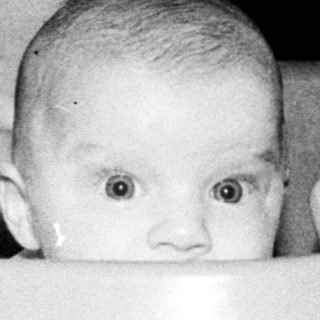 Baby sitting in a plastic tub.