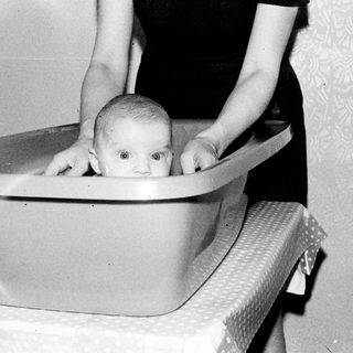 Baby sitting in a plastic tub.