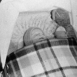Baby sleeping in a stroller with a cupcake.