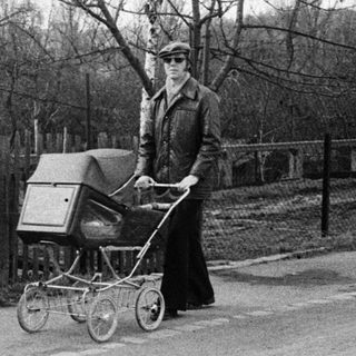 Woman pushing baby buggy on quiet road.