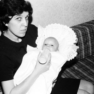 Woman holding baby in vintage nursing pose.