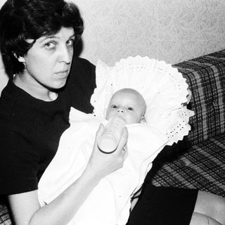 Woman holding baby in vintage nursing pose.