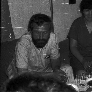 Three people seated at a table during an indoor event.
