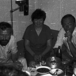 Three people seated at a table during an indoor event.