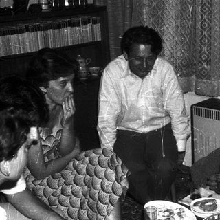 Family gathering around a table eating indoors.