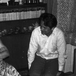 Two people sitting indoors, engaged in conversation.