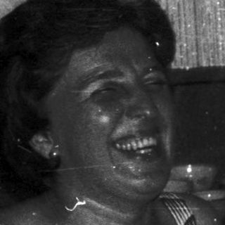 Two people laughing together indoors.