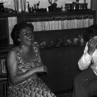 Two people laughing together indoors.