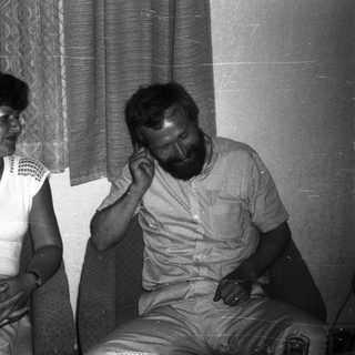 Two people sitting indoors, engaged in conversation.