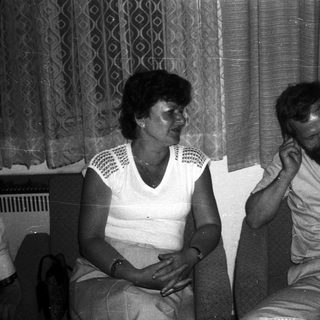 Two people sitting indoors, engaged in conversation.