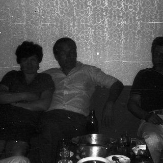 Three people sitting indoors on a couch.
