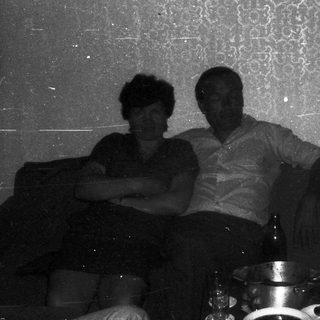 Three people sitting indoors on a couch.