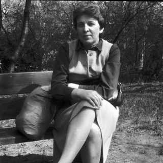Woman sitting alone on park bench outdoors.