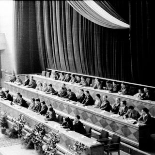 Historic conference or assembly hall with delegates seated.