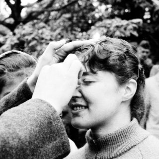 A woman being playfully kissed on the forehead by someone outdoors.