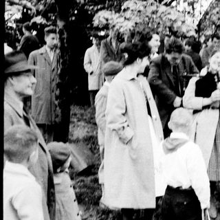 Group of people outdoors in early 20th-century clothing.