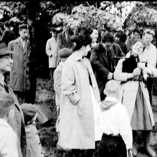 Group of people outdoors in early 20th-century clothing.
