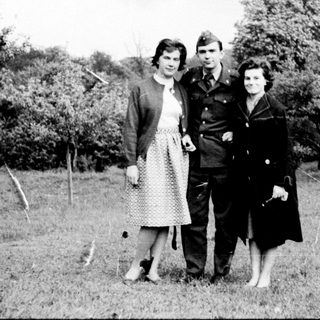 Three individuals in mid-20th-century attire posing outdoors.