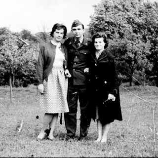 Three individuals in mid-20th-century attire posing outdoors.