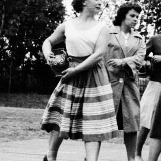 Group of women dancing in 1950s-style skirts outdoors.