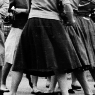 Group of women dancing in 1950s-style skirts outdoors.